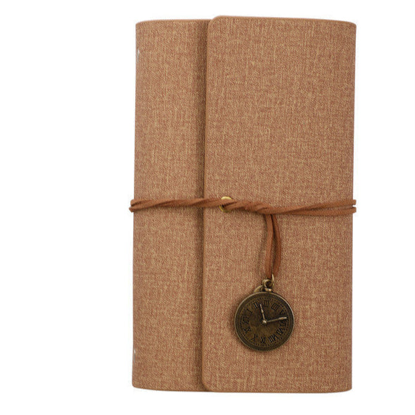 Brown textured PU leather notebook with a decorative charm on a white background