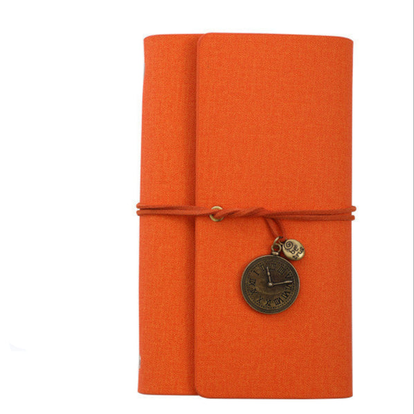 Orange PU leather textured notebook with a charm on a white background.