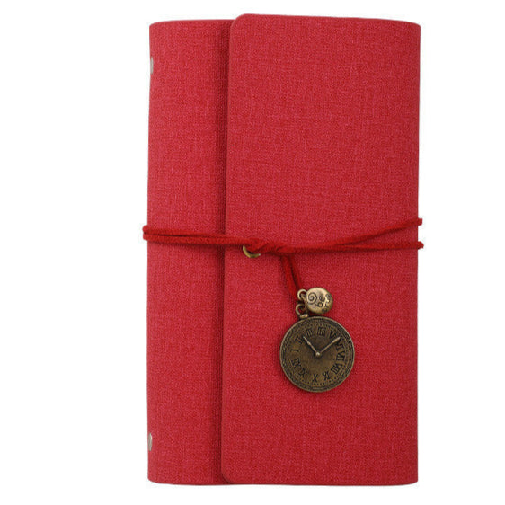 Red vegan PU leather textured notebook with a decorative charm on a white background